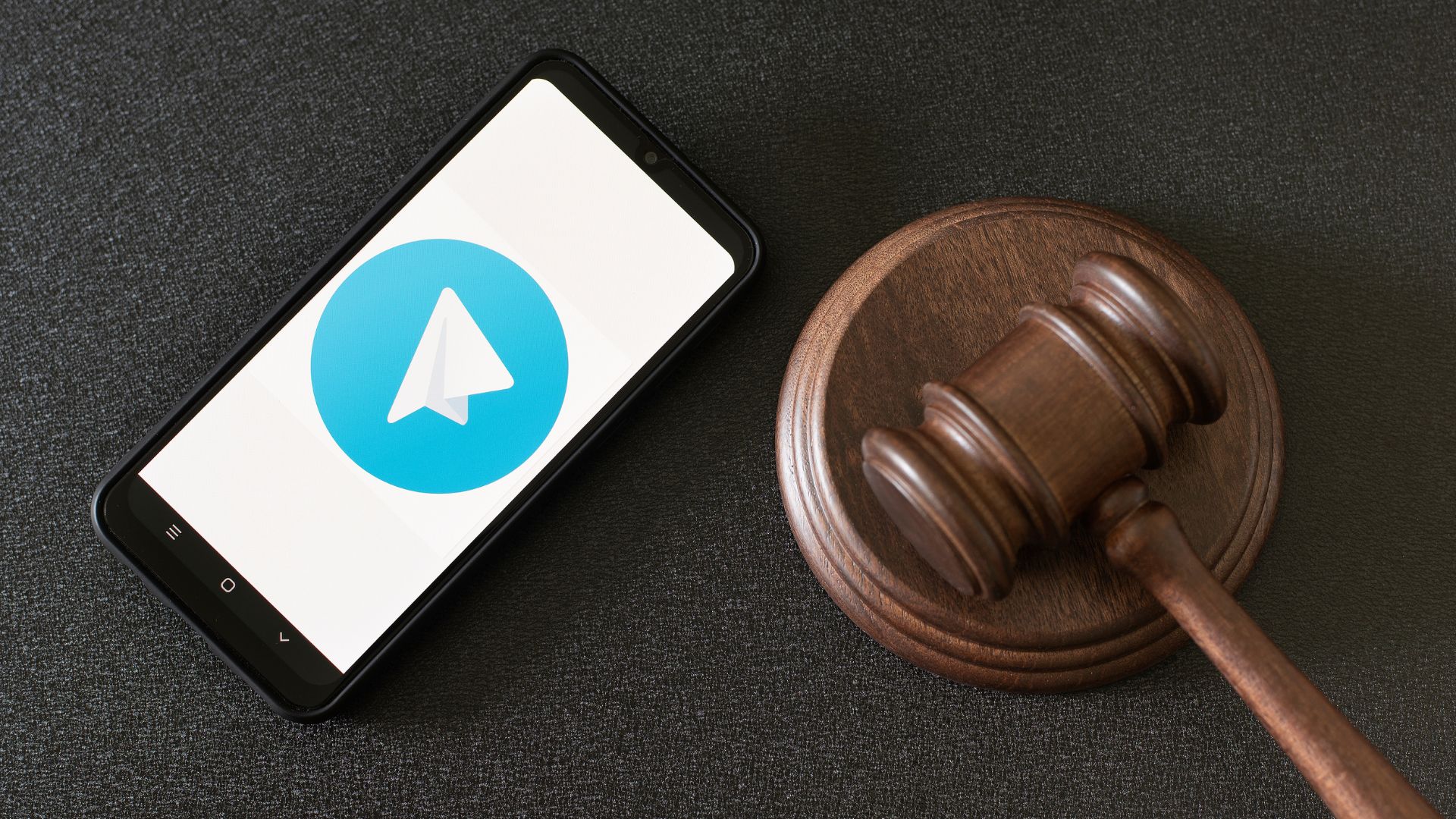 Смартфон з логотипом Telegram та судовий молоток як символ штрафу за рекламу казино