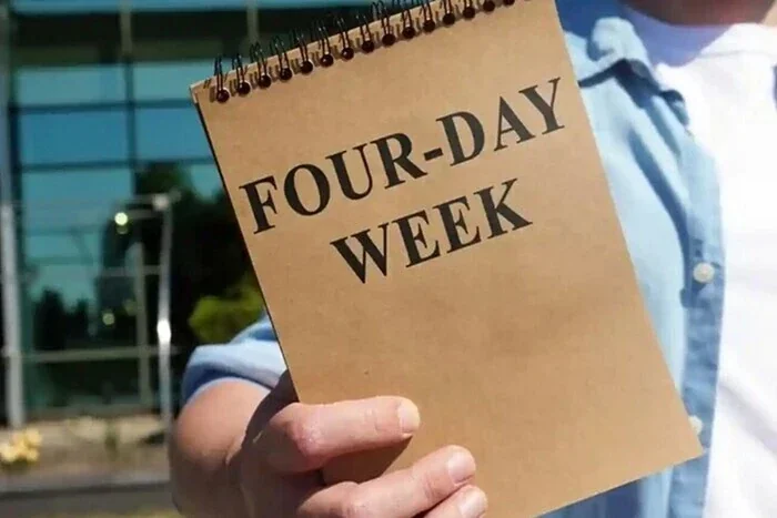 Рука держит блокнот с надписью Four-Day Week в петиции о четырёхдневной неделе