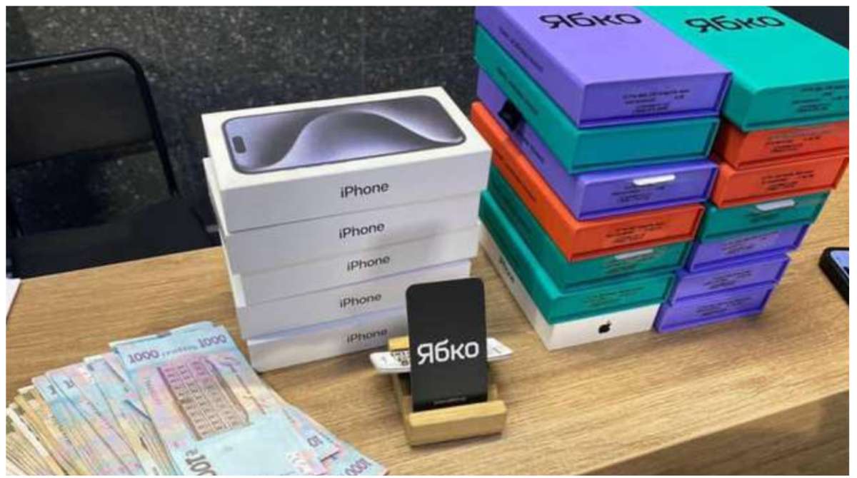 Коробки iPhone та Ябко з пачками гривень на столі