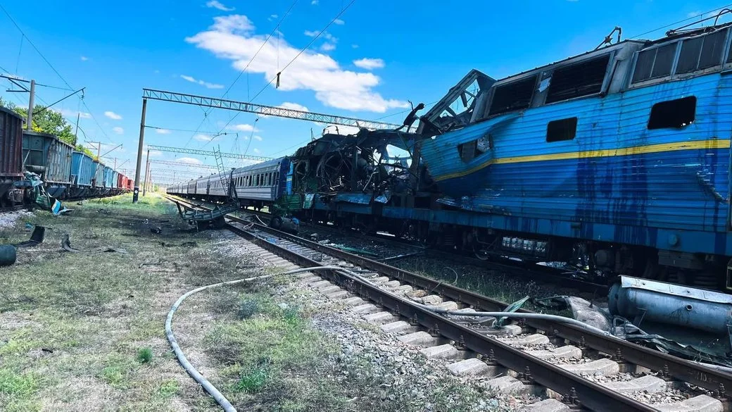 Зруйнований синій пасажирський локомотив і вагони на залізничних коліях