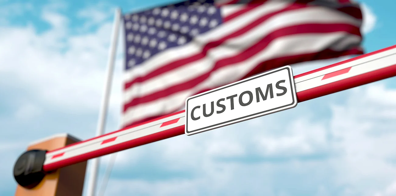 Митний шлагбаум США з прапором на тлі нових правил для відправлень