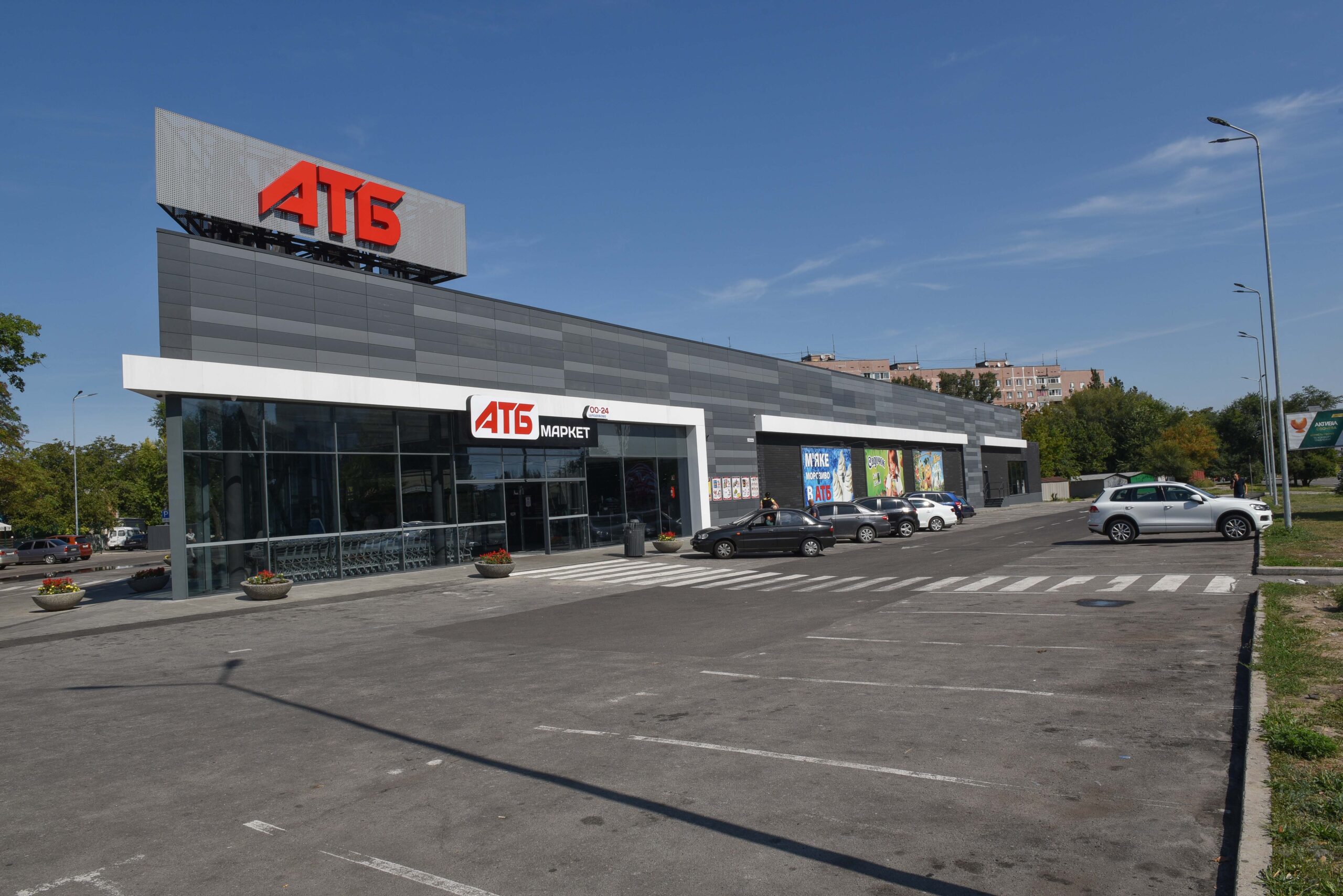 Сучасний супермаркет АТБ-Маркет з парковкою автомобілів під чистим небом